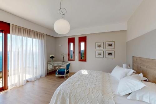 a white bedroom with a bed and a desk at Ocean Villas Complex in Agia Pelagia
