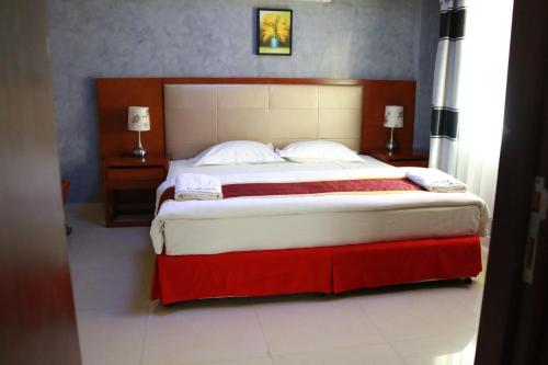 a bedroom with a large bed with red and white sheets at Horizon Hotel Apartments - الأفق للشقق الفندقية in Al Khawḑ