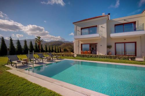 a villa with a swimming pool in front of a house at Ocean Villas Complex in Agia Pelagia