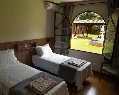 a room with two beds and a chair and a window at Hostel SLG in Maringá