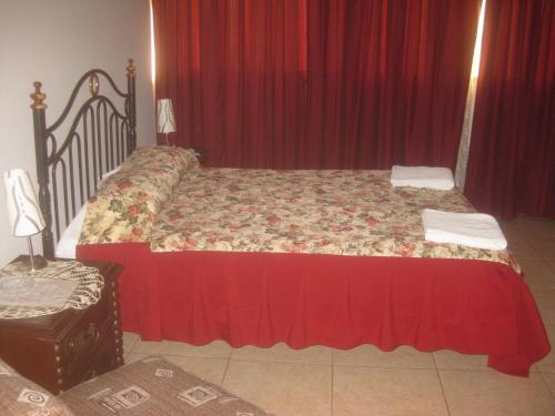 a bedroom with a large bed with red curtains at Hostal Camiluz in Nazca