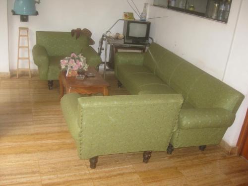 a living room with two green couches and a table at Hostal Camiluz in Nazca