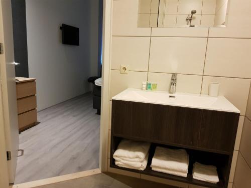 a bathroom with a sink and white towels at B&B de Wilhelminaschool in Aalten