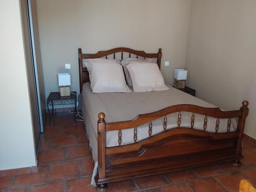 a bedroom with a large wooden bed with white pillows at Casa Myrta 3 étoiles in Porto-Vecchio