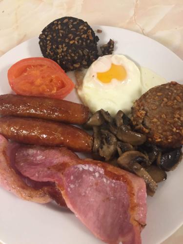 a plate of breakfast food with eggs sausage and mushrooms at Coral Gables Guesthouse & Campsite in Rosslare