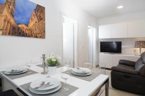 a living room with a table with plates and wine glasses at Holiday Home Aspalathos - with free parking, near the beach, a few minutes' walking distance to the UNESCO Palace in Split