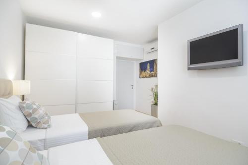 a white room with two beds and a flat screen tv at Holiday Home Aspalathos - with free parking, near the beach, a few minutes' walking distance to the UNESCO Palace in Split