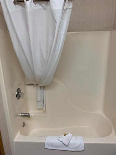 a white bath tub with a shower curtain and a towel at The Gunnison Inn at Dos Rios Golf Course in Gunnison