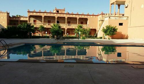 une piscine d'eau en face d'un bâtiment dans l'établissement Hotel Mandar Saghrou Tazakhte, à Kelaat-M'Gouna