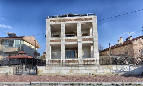 a tall white building in front of a building at EL NAZAR STONE SUİTE in Uchisar
