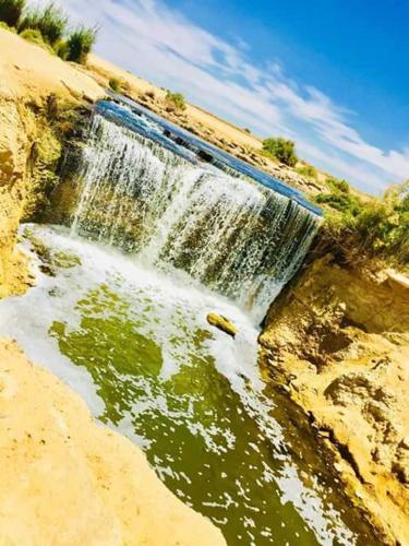 a waterfall on the side of a hill with water at Tunis Village Chalet in Fayoum Center