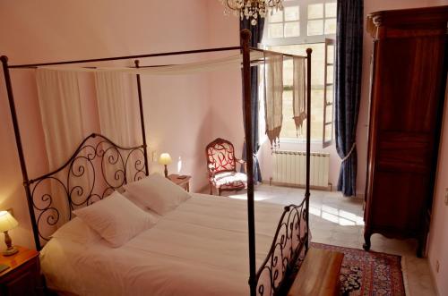 a bedroom with a canopy bed and a chair at La Pivoine in Sarlat-la-Canéda