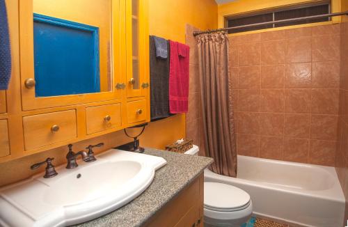 a bathroom with a sink and a tub and a toilet at Hawaiian Sunrise Vacation House in Pahoa