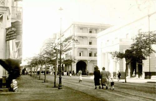 a group of people walking down a street in front of a building at De La Poste in Port Said