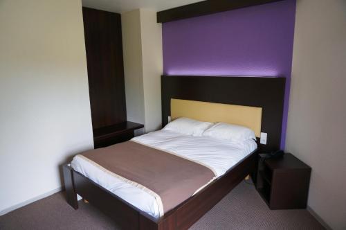 a bedroom with a bed with a purple head board at Les Portes d'Apcher in Saint-Chély-dʼApcher