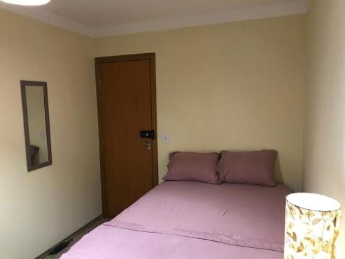 a bedroom with a bed with pink sheets and a mirror at GA1-Hospedagem Próximo ao Aeroporto de Guarulhos in Guarulhos