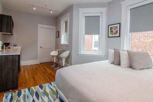 a bedroom with a large white bed and a kitchen at A Stylish Stay w/ a Queen Bed, Heated Floors.. #32 in Brookline
