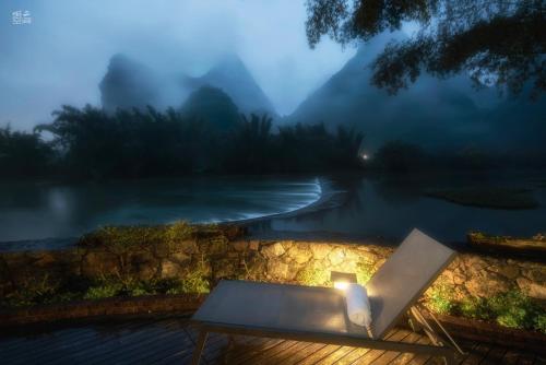 a bench sitting next to a lake with a candle at The Apsara Lodge-Airport or TS Free pick-up over 3 nights in Yangshuo