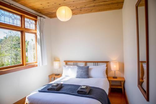 a bedroom with two beds and two windows at The Church Accommodation in Hahei