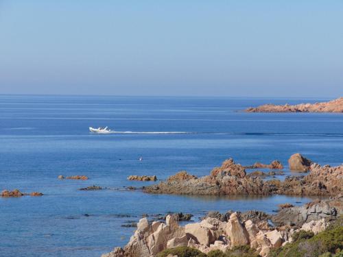 a boat in the ocean with rocks in the water at piccolo monolocale al porticciolo in Isola Rossa
