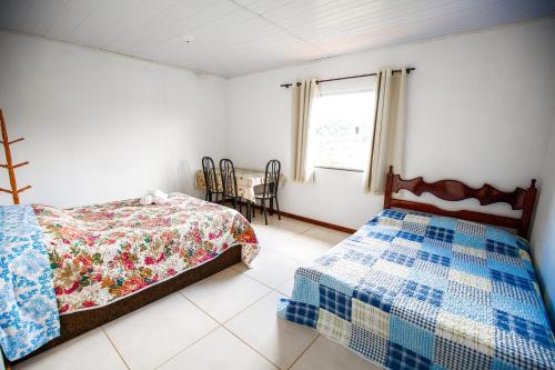 ein Schlafzimmer mit zwei Betten und einem Tisch und einem Fenster in der Unterkunft Pousada Bela Vista in Conceição da Ibitipoca