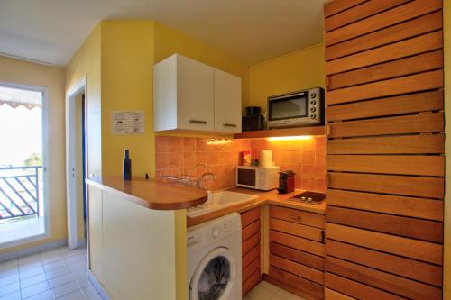 a kitchen with a washing machine and a microwave at Appartement T3- Résidence Manganao in Saint-François