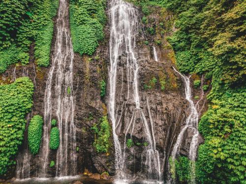 two waterfalls on the side of a rock wall at Desa Eko in Munduk