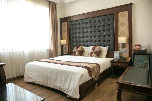 a bedroom with a large bed with a large headboard at CityBay Palace Hạ Long Hotel in Ha Long