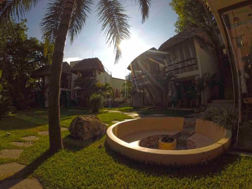 a building with a palm tree and a fountain in the grass at Mocca Hotels in Tepoztlán