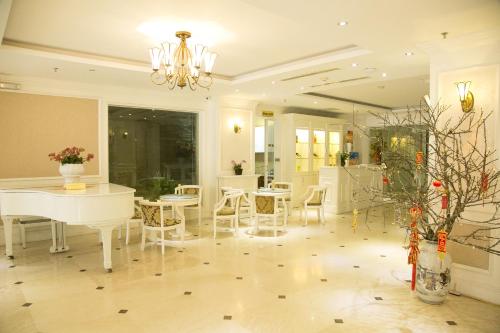 a dining room with white tables and chairs and a chandelier at CityBay Palace Hạ Long Hotel in Ha Long