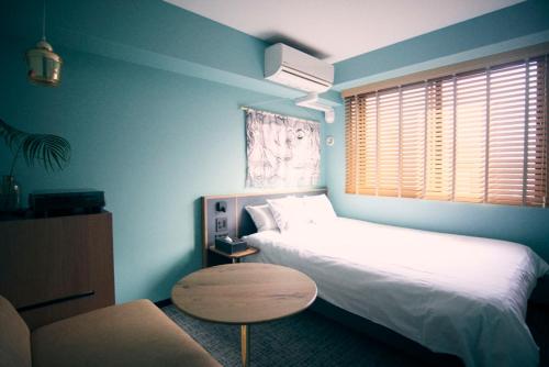 a bedroom with two beds and a table and a couch at Hotel She, Kyoto in Kyoto
