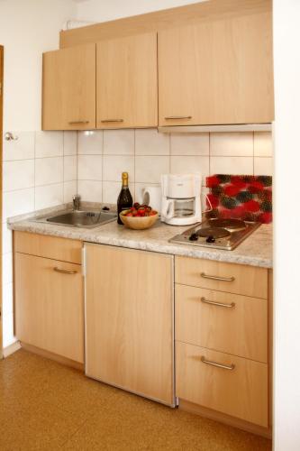a kitchen with a sink and a counter with a bottle of wine at Appartementhaus Albrecht in Bad Füssing