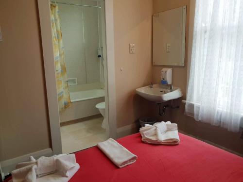 un baño con una cama roja con toallas. en Gretna Hotel Taihape, en Taihape