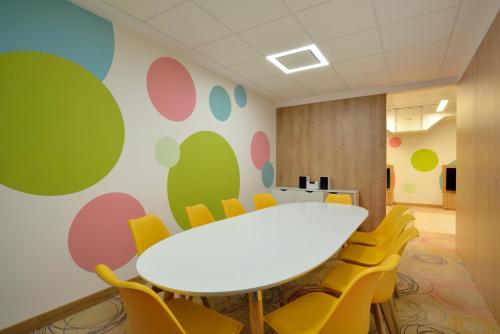 a conference room with a white table and yellow chairs at Hotel Avangarda in Różan
