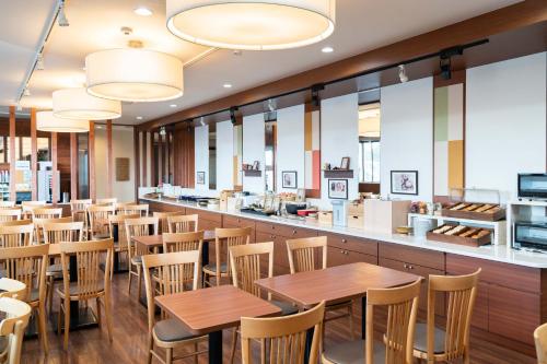 a restaurant with wooden tables and chairs and a counter at Vessel Hotel Kumamoto Airport in Ozu