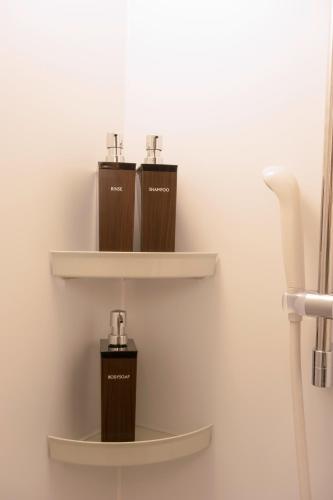 a bathroom with two shelves withodorins on the wall at BEACH AND FIELD INN in Sapporo