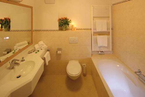a bathroom with a tub and a toilet and a sink at Ruhehotel & Naturresort Rehbach - Adults only in Schattwald
