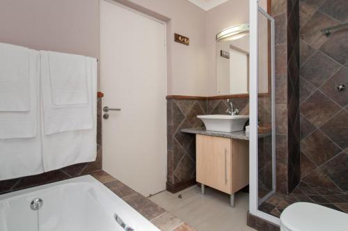 a bathroom with a white tub and a sink at Whale Away Guest House in Hermanus