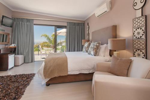 a bedroom with a large bed and a couch at Whale Away Guest House in Hermanus
