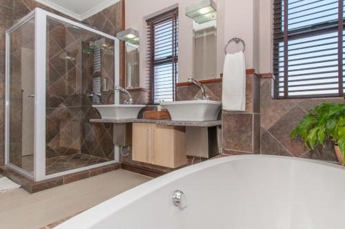 a bathroom with two sinks and a bath tub at Whale Away Guest House in Hermanus