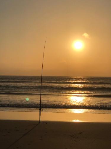a fishing pole on the beach at sunset at Relaxarna in Robe