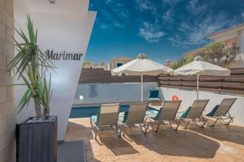 a group of chairs and umbrellas next to a swimming pool at Marimar villa in Protaras
