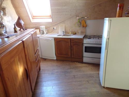 una cucina con armadi in legno e frigorifero bianco di Petite Ferme d'Autrefois a Saint-Georges-Nigremont