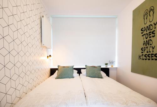 1 dormitorio con 1 cama con sábanas blancas y almohadas azules en Appartement Zuyd, en Zandvoort