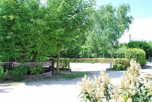 a park with a fence and a tree and bushes at Hotel Gut Moschenhof in Düsseldorf