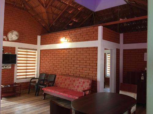 a room with a red couch and a table and chairs at Marsim Holiday Resort in Vythiri