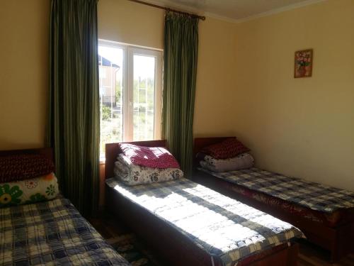 a room with two beds and a window with curtains at AltynAi Guest House in Cholpon-Ata