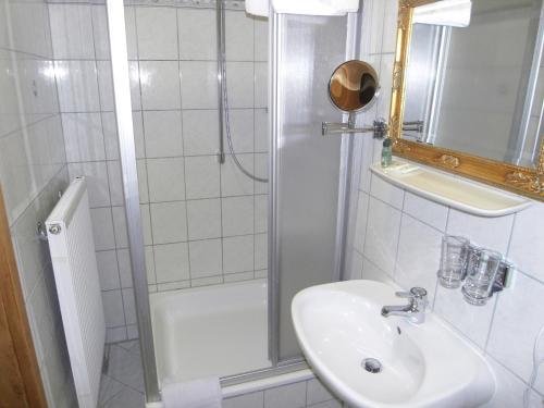 a white bathroom with a shower and a sink at Posthotel Sachrang in Sachrang