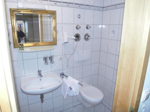 a bathroom with a sink and a toilet and a mirror at Posthotel Sachrang in Sachrang