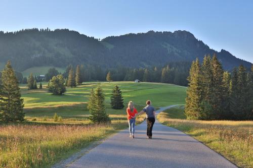 a man and a woman walking down a road at Ruhehotel & Naturresort Rehbach - Adults only in Schattwald